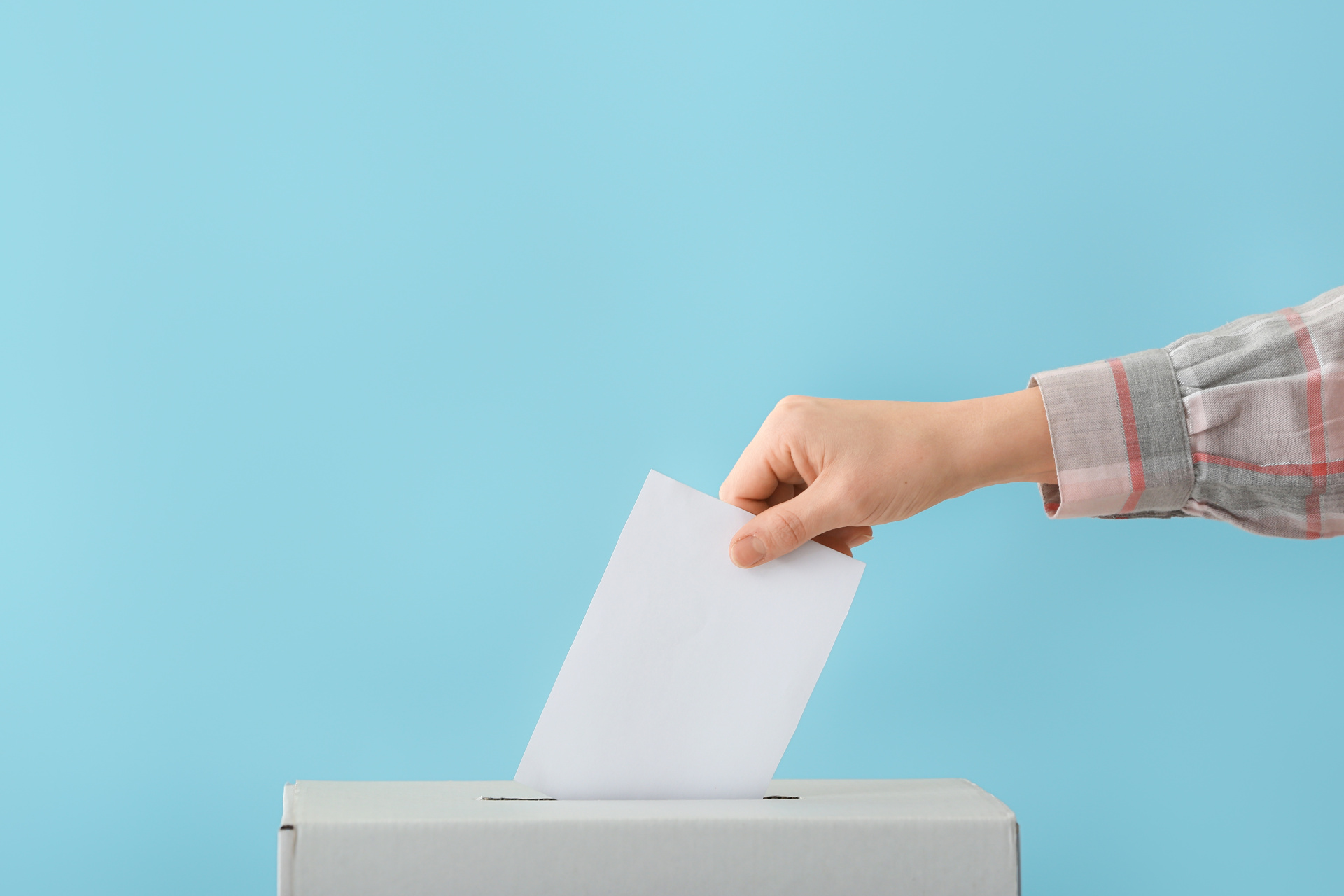Elections Woman dropping her ballot paper into a ballot box.