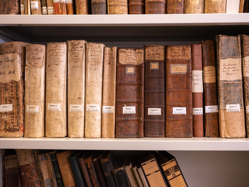 Mehrere Archivbände in einem Regal im Kitzinger Stadtarchiv.