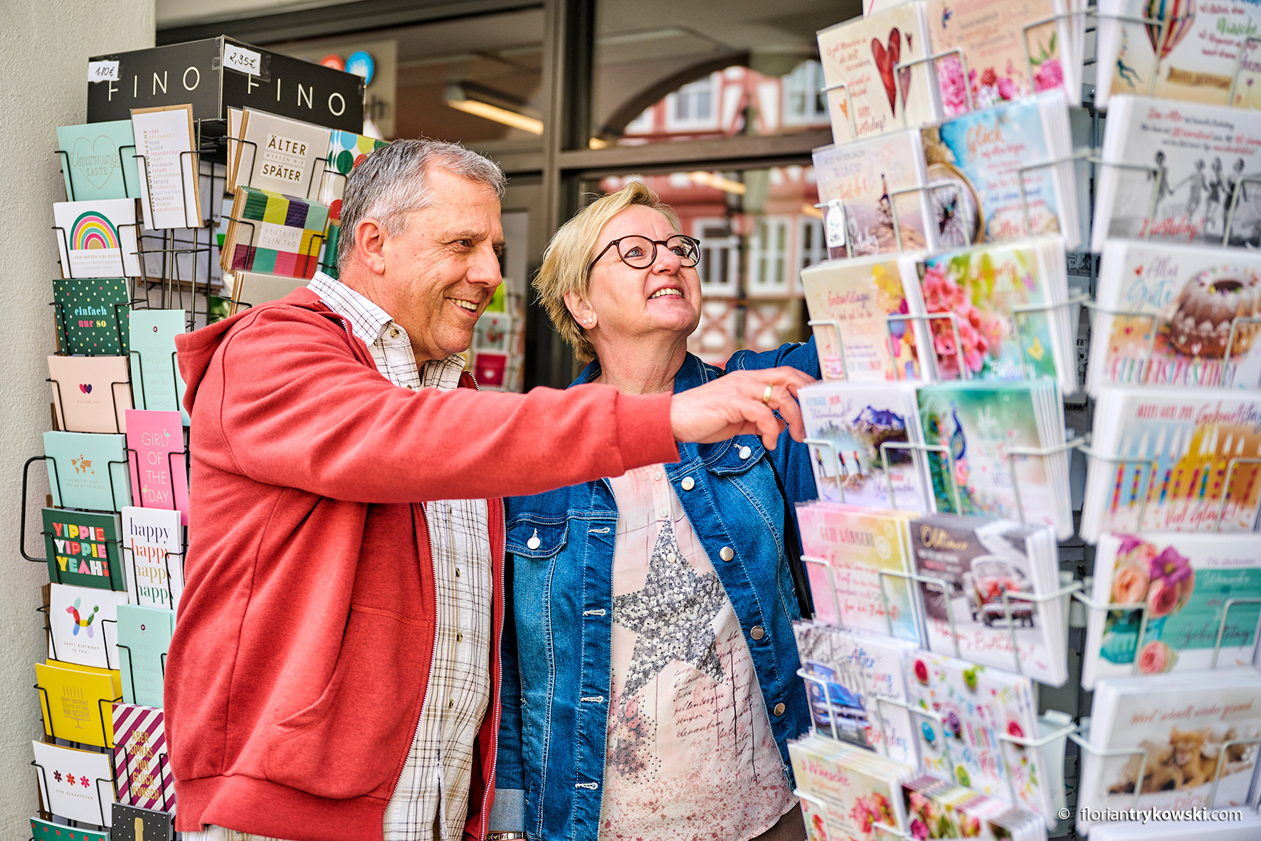 A man and a woman stand in front of a stand with greeting cards