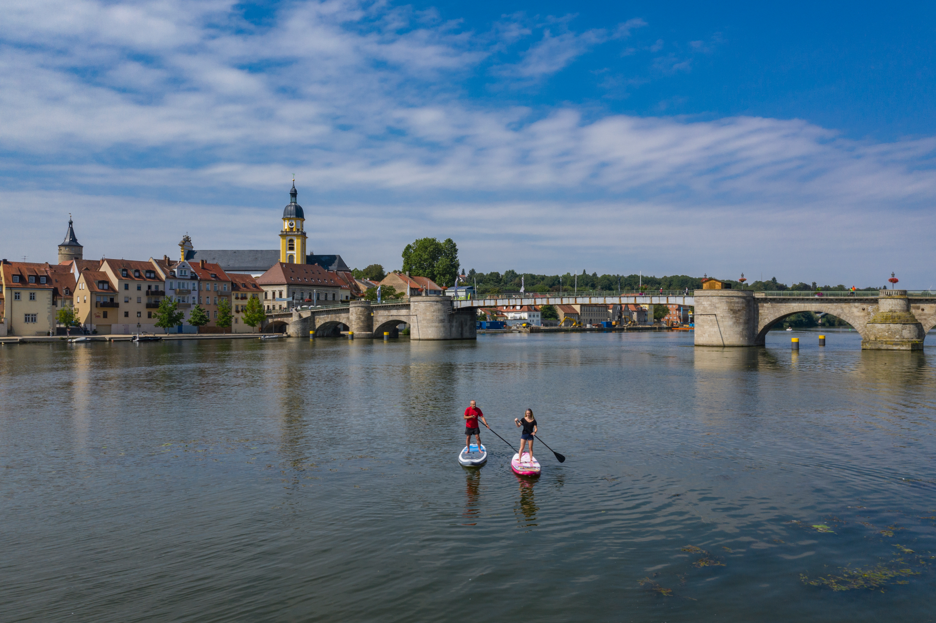 Zwei Leute machen Stand Up Paddling auf dem Main mit Panorama von Kitzingen im Hintergrund