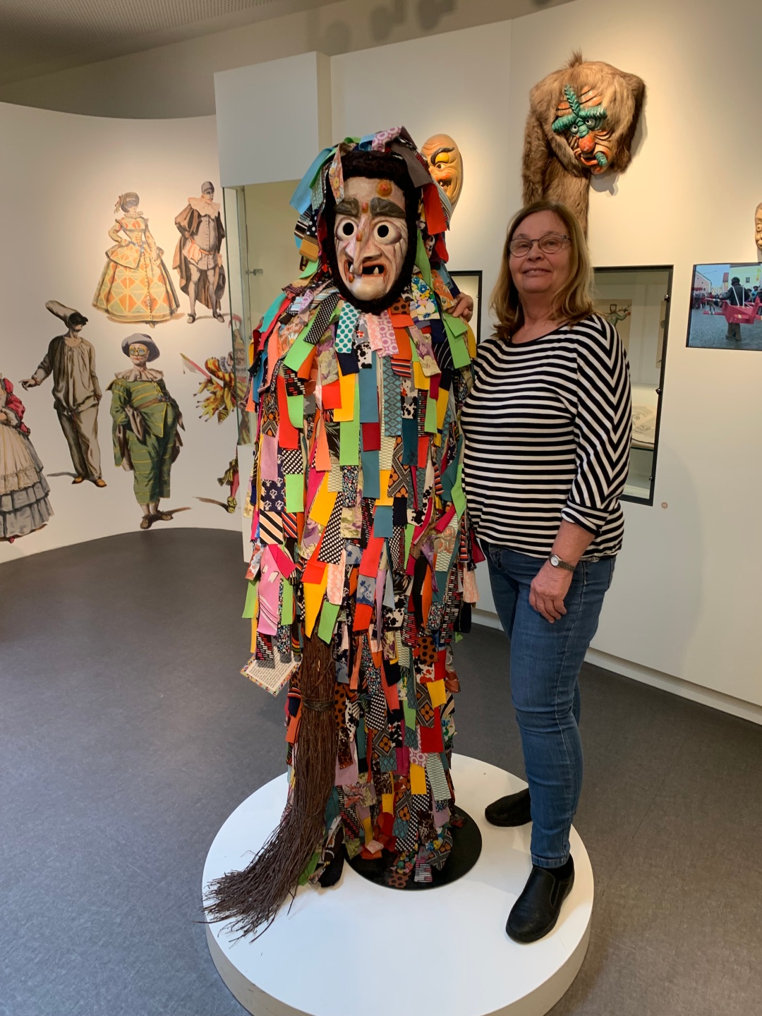 A tour guide stands next to a colourful carnival figure