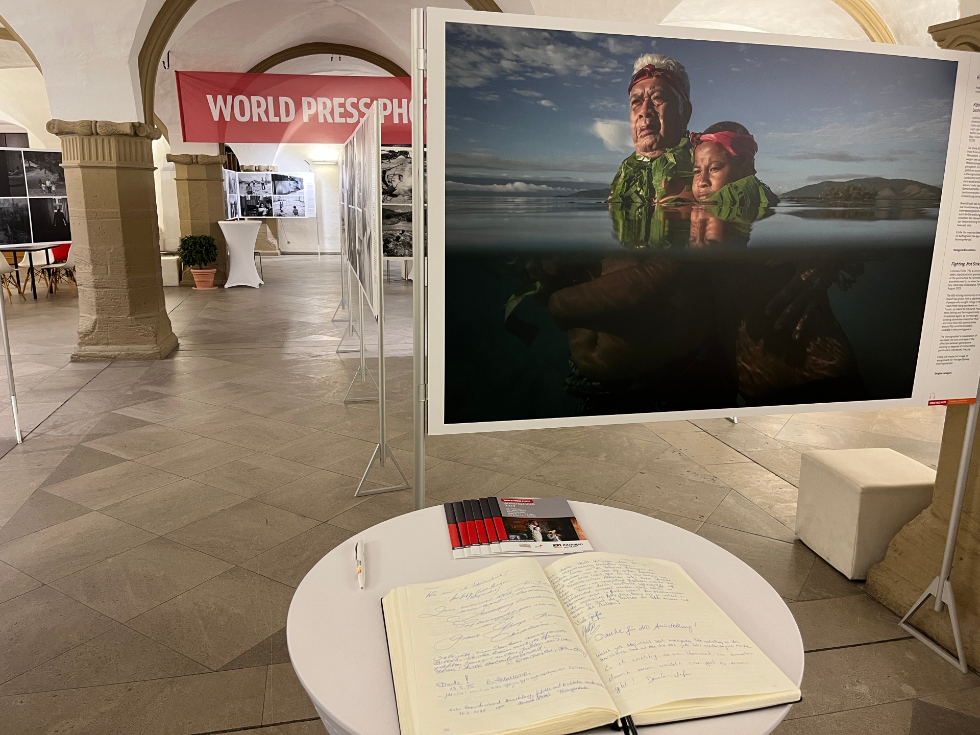 Exhibition in the town hall Panels with various pictures in front of the World Press photo banner and the guest book in the Kitzingen town hall.