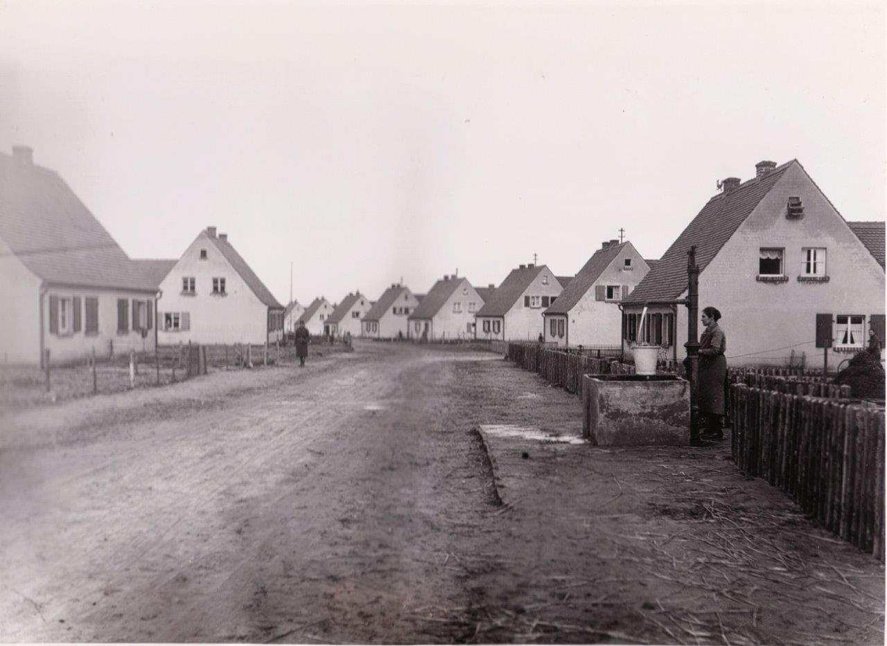 Texasweg um 1930 Anselm Caliz war der erste Siedler in der Kitzinger Siedlung. Der größte Stadtteil Kitzingens ist über 100 Jahre alt. Am Haus von Anselm Caliz, im Texasweg 3, ist eine Gedenktafel angebracht.